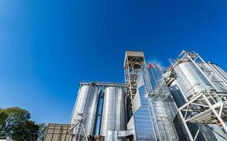 Full length view of the tanks and agricultural silos of grain elevator storage. Loading facility building exterior. View from below photo