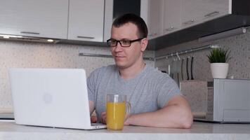 Young male freelancer in glasses uses a laptop while working from home on the Internet looking at the screen while enjoying remote work video