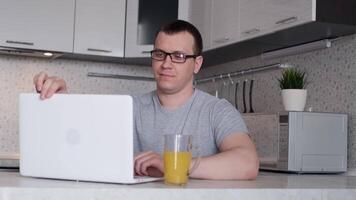 Young male freelancer finishes a day of remote work from home and drinks orange juice video