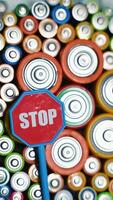 Old used batteries type AA, AAA, D and stop sign rotate in a circle. Vertical video