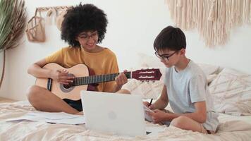 musica insegnamento, musicale formazione scolastica, giocando chitarra, tempo insieme. africano americano donna insegna ragazzo per giocare chitarra utilizzando il computer portatile. video