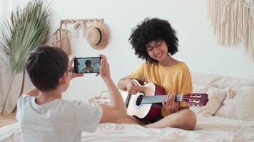arte blogueiros, conectados lição gravação, mulher blogueiro, jogando guitarra. blogueiros músicos registro uma lição usando uma Smartphone video