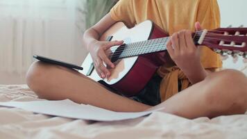 spielen Gitarre, online selbst lernen, Kunst Unterricht, verwenden ein Gerät. afro amerikanisch Mädchen Lernen zu abspielen das Gitarre mit ein Smartphone. Nahansicht video