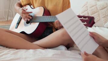 música enseñando, musical educación, jugando guitarra, hora juntos. mujer enseñando música lecciones a chico sentado en cama a hogar video