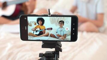 Art Bloggers, Online Lesson Recording, Woman Blogger, Playing Guitar. Cheerful kids bloggers are recording guitar lessons on a smartphone. Smartphone screen video