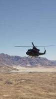 A helicopter flying over a desert with mountains in the background video