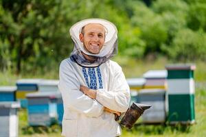 The beekeeper stands crosshands near apiary. Apiculture. Apiary. photo