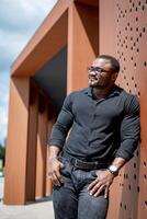 Stylish man in black shirt walking out the urban street. Handsome young model in elegant cloth. photo