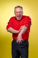 Senior man is standing with open mouth pretending screaming. Isolated against yellow background. Happy emotions. Rolling up sleeves. photo