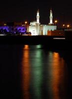 noche escena en el recurso ciudad. presentando el faro torre con luces reflexión. foto