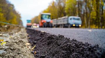 Large view on the road machinery working on the new road construction site. Fresh asphalt in front. Blurred machinery on background. photo