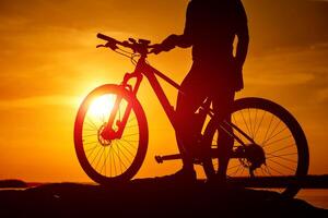 puesta de sol sombra de ciclismo hombre. silueta de noche ciclista foto