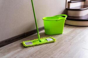 Mop with green microfiber rag, green plastic handle and bucket. Housekeeping concept. photo