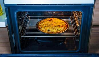 Pizza Cocinando en un redondo bandeja en un horno. hecho en casa Pizza. foto