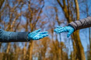 Two hands trying to hold each other in park background. The concept of a pandemic, quarantine, prevention of viruses, diseases. photo