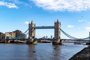 soleado día ver de el icónico torre puente terminado el Támesis en Londres, con claro azul cielo y mullido nubes foto