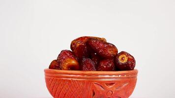 Dried sweet dates in a clay bowl on a white background close-up. Rotation video