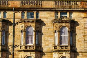 Close-up of a classic sandstone building facade with ornate windows and architectural details in warm sunlight in Harrogate, England. photo