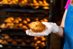 Hand holding cake or muffin. Factory oven background. photo