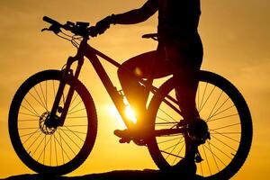 Silhouette of a bike with a man on sky background on sunset. Detailed photo. Closeup photo