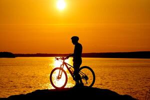 silueta de el ciclista montando en un Deportes bicicleta a puesta de sol. activo estilo de vida concepto. foto