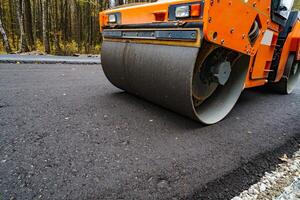 Road roller flattening new asphalt. Heavy vibration roller at work paving asphalt, road repairing. Selective focus. photo