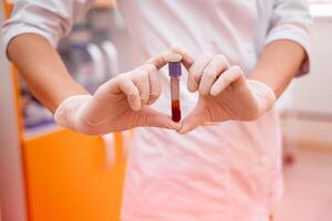 Scientist hold a blood sample. Test tube full of blood for checking coronavirus. photo