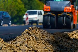 Road roller flattening new asphalt. Heavy vibration roller at work paving asphalt, road repairing. Selective focus. photo