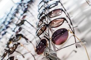 Sunglasses in the shop display shelves. Stand with glasses in the store of optics photo