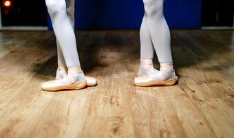 Legs of young ballerinas. Rehearse in the ballet class. Dressed in white pantyhose and ballet shoes. Pointe shoes concept. photo