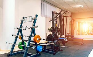 Modern light gym. Sports equipment in gym. Barbells of different weight on rack. photo