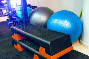 Big blue, and grey fitness balls near the grey wall in gym. Fitness yoga and pilates hall with sport equipment. Close-up photo