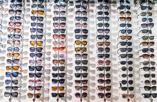 Sunglasses in the shop display shelves. Stand with glasses in the store of optics. photo