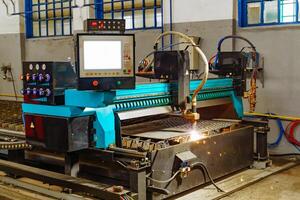 metalúrgico láser máquina trabajos a corte metal interior en el fábrica. industrial equipo para corte metal en proceso con espumoso ligero. foto