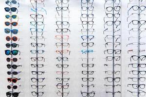Sunglasses and glasses in the shop display shelves. Stand with glasses in the store of optics. photo