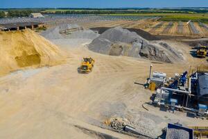 An industrial asphalt plant surrounded by piles of gravel. Asphalt mixture. Harmful production. A mixture of bitumen and gravel, a mix machine. Aerial view photo