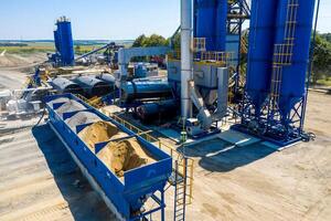 Equipment for production of asphalt, cement and concrete. Concrete plant. High tower of an asphalt plant. Harmful production. A mixture of bitumen and gravel, a mix machine. Aerial view. photo