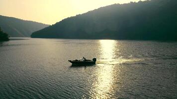 Aerial view Tranquil River Sunset with Boat, A boat glides on a river shimmering with the golden light of the setting sun. video