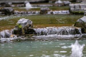 Tranquil mini waterfall over rocks in a serene forest stream. photo