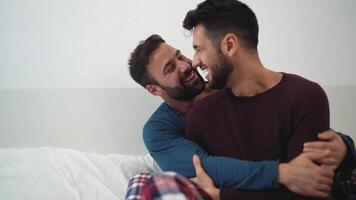 two men are hugging while sitting on a bed video