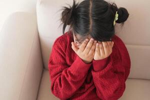 a upset child girl cover her face with hand photo