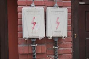 Two electrical boxes with lightning bolt on brick wall photo