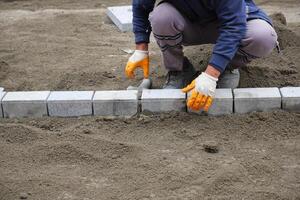 a worker laying concrete bricks on each other for building a new sidewalk photo