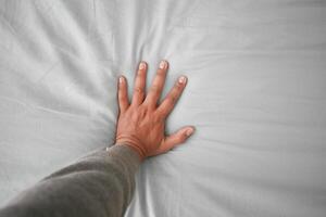 Hand touching and pressing orthopedic mattress on bed. photo