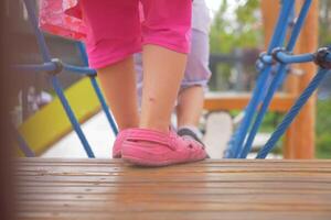 un pequeño niña en rosado Zapatos es en pie en un de madera cubierta foto