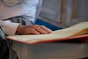 muslim man hand holding Holy book Quran at mosque photo