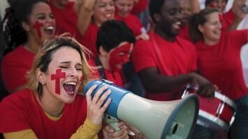 hembra fútbol americano aficionados exultante mientras acecho un fútbol juego a el estadio - mujer con pintado cara y megáfono alentador su equipo - deporte entretenimiento concepto video