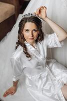 portrait of an incredibly beautiful girl bride in a white robe in the bedroom, the bride poses in the morning before the wedding ceremony. photo