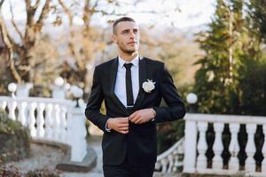 Portrait of a handsome young groom on an autumn day outdoors in an elegant suit. Outdoor photo. Handsome man in a business suit. photo