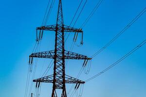 Power poles of a high voltage lines bearing electricity across towns and villages. Selective focus. photo